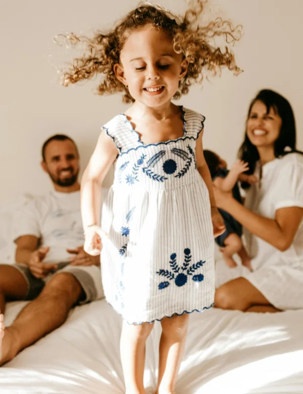 Home hero - little girl jumping on a bed while her parents happily watch